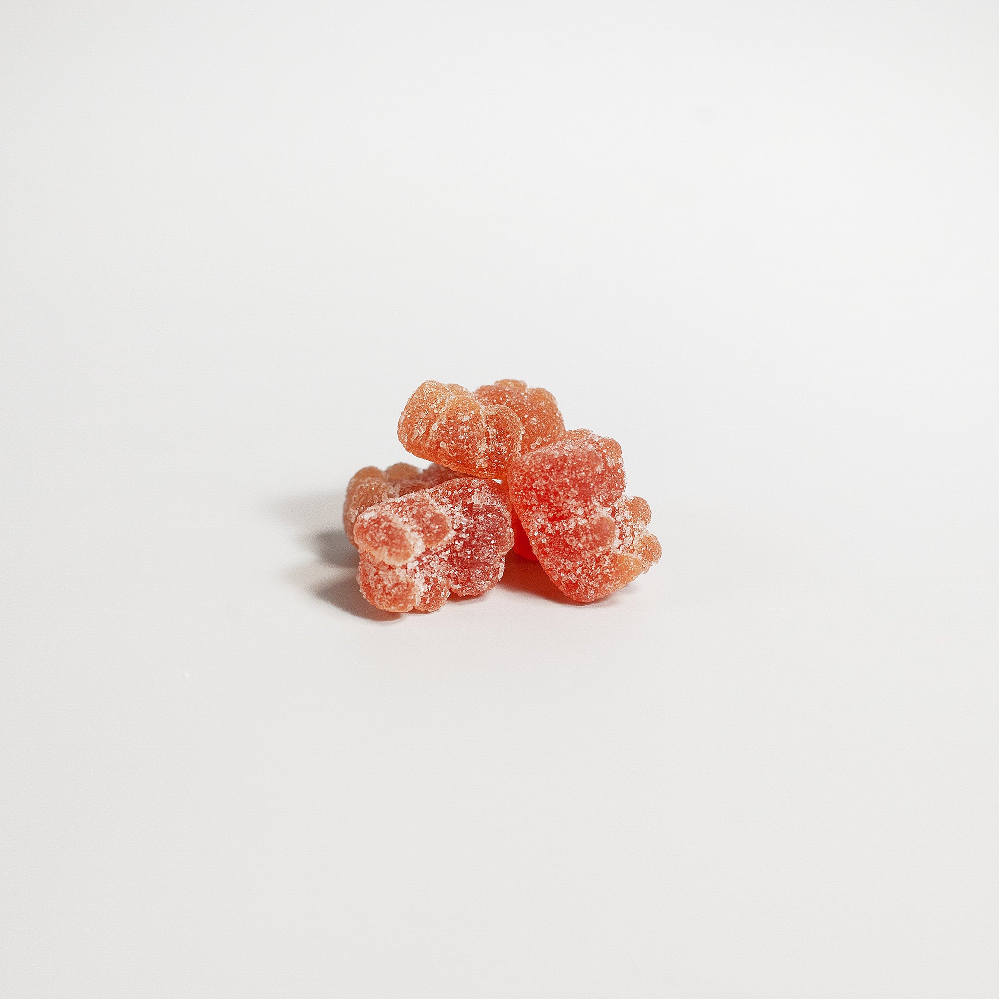 Three pink gummy bears on a white background